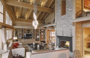 A spacious living room with a fireplace, wooden beams, and a television. - 5-Bedroom Chalet with Wellness Area (La Clusaz)