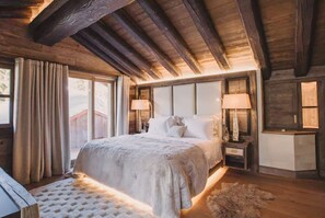 A bedroom with a large bed, wooden beams, a window with curtains, and a nightstand with a lamp. - 6-Bedroom Chalet with Wellness Area (La Clusaz)