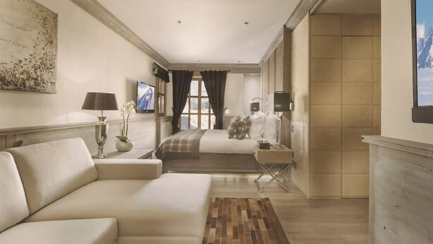 Quarto de hotel com uma cama grande, um sofá, uma TV e uma lareira.