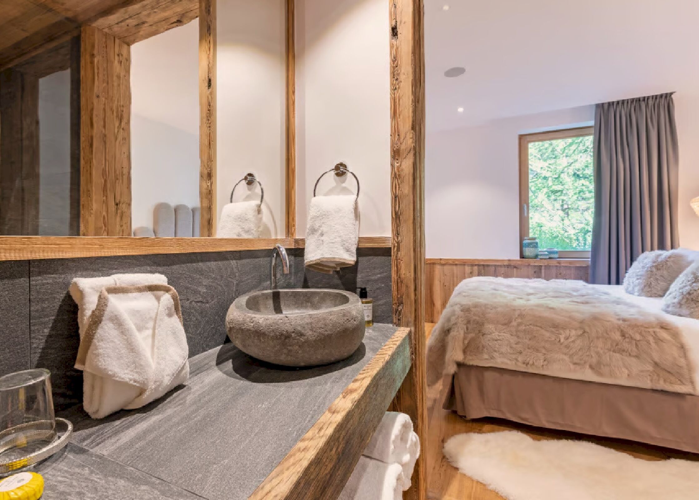 A bathroom with a stone sink, wooden vanity, and a large mirror.