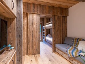 A wooden interior with bunk beds, a sofa, and a mirror. - 5-Bedroom Chalet with Wellness Area (Les Deux Alpes)