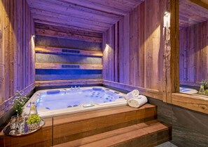 Ein Holzblock-Interieur mit Whirlpool, Holztreppe und Spiegel, der den Raum widerspiegelt.
