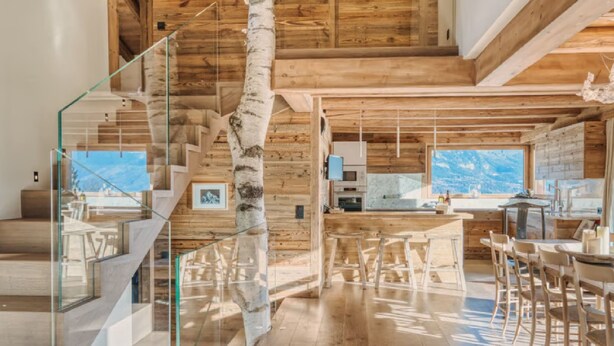 A modern interior with a wooden staircase, glass railings, a dining area, and a kitchen. - 5-Bedrooms Chalet with Views (Les Allues)