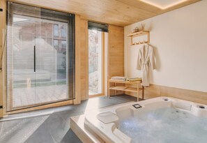 A spa room with a hot tub, wooden shelves, and a sliding glass door.