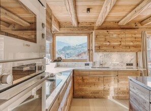 Eine Küche mit Holzausstattung, einem Bosch-Ofen, einer Marmorarbeitsplatte und Blick auf eine Stadt durch ein Fenster.