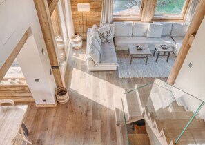 Ein modernes Interieur mit Holzboden, einem weißen Sofa, einem kleinen Tisch und einer Treppe.
