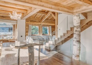 Ein modernes Interieur mit Holzbalken, einer Glastreppe und einer Sitzecke mit heller Möbelgebung.