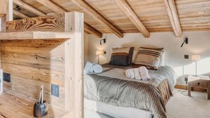 A wooden ceiling with exposed beams, a bed with striped bedding, and a bedside table with a lamp. - 5-Bedrooms Chalet with Views (Les Allues)