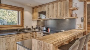 Eine moderne Küche mit Holzschränken, einem großen Fenster und einer Bar mit Sitzgelegenheiten.