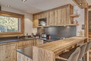 Eine moderne Küche mit Holzschränken, einem großen Fenster und einer Bar mit Sitzgelegenheiten.