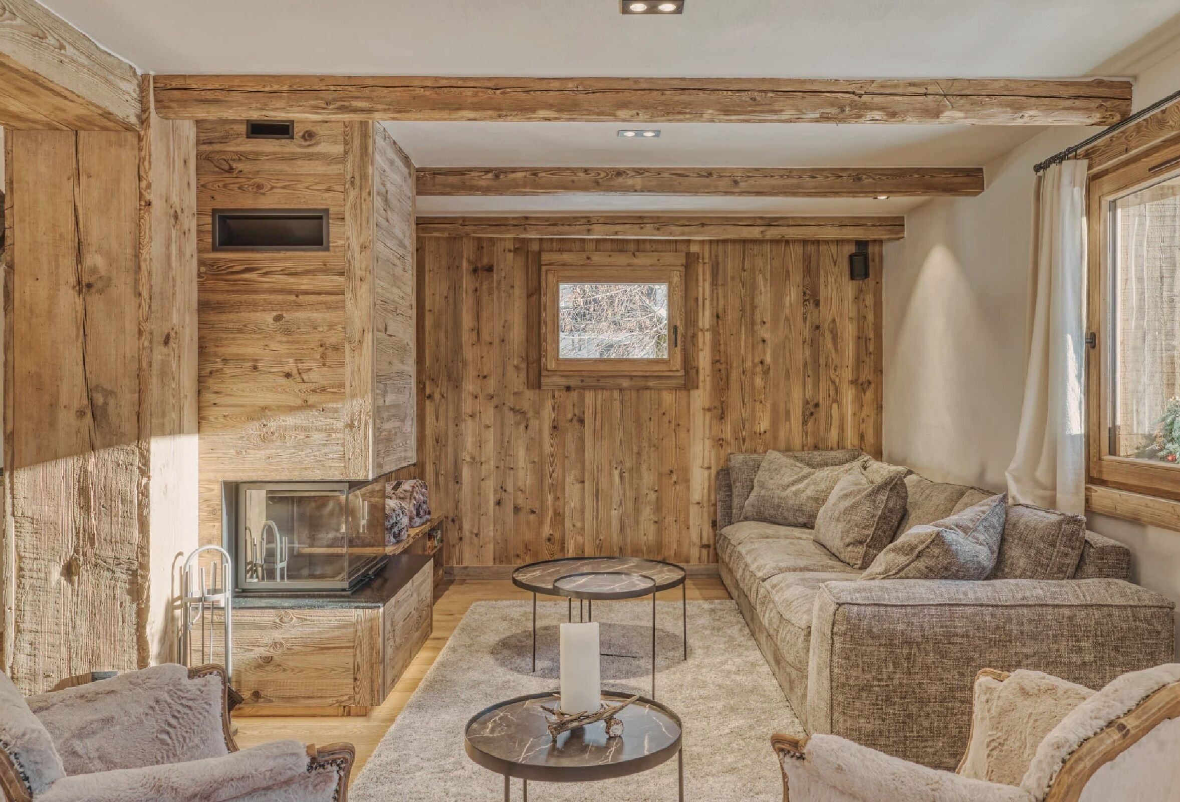 A cozy room with wooden walls, a fireplace, a sofa, and two side tables.
