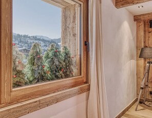 Une pièce avec une fenêtre à cadre en bois, une lampe et une vue sur un paysage enneigé.