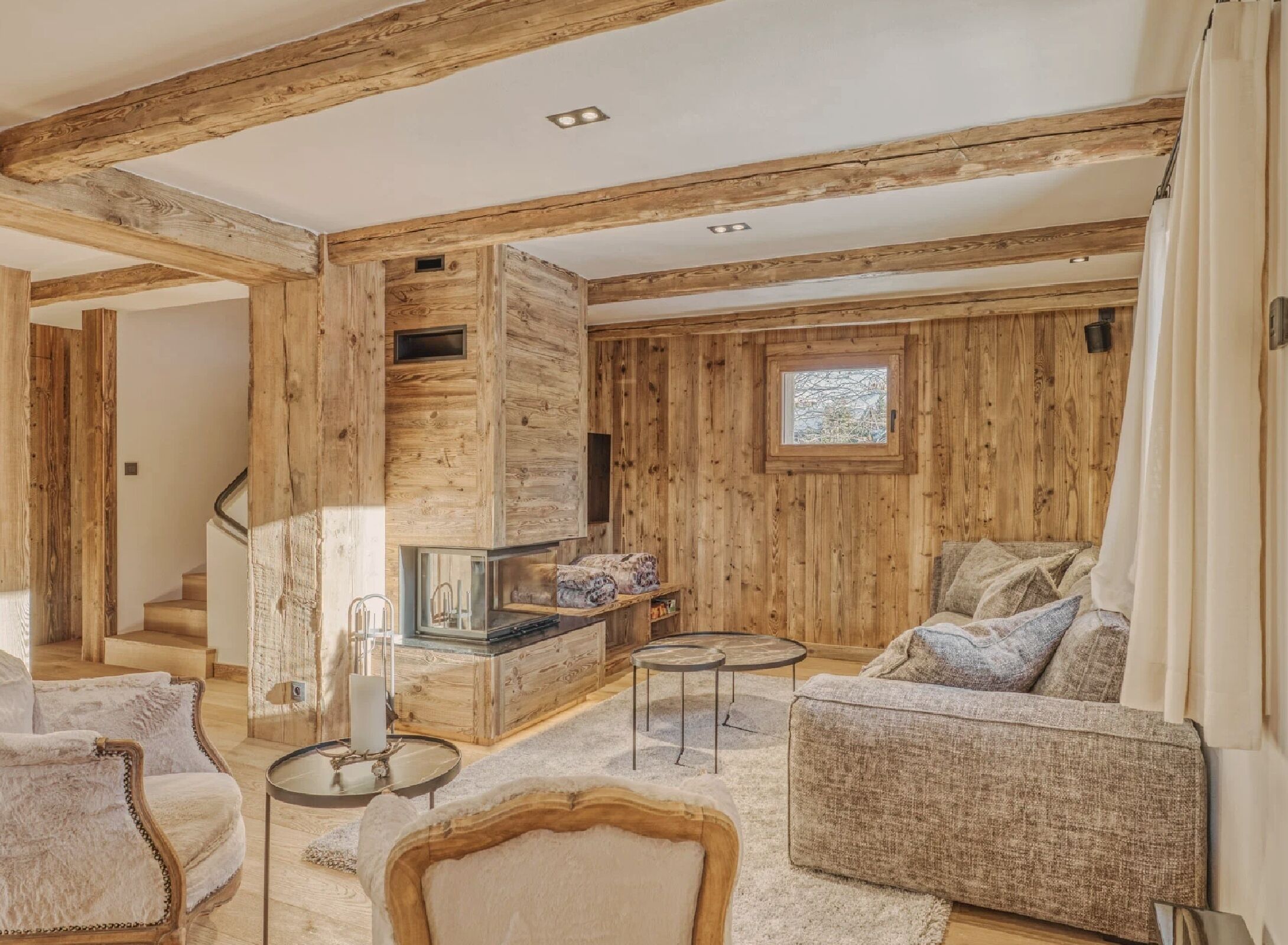 Ein Holzinnenraum mit Kamin, Sofa und Wendeltreppe.