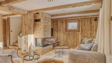 Ein Holzinnenraum mit Kamin, Sofa und Wendeltreppe.