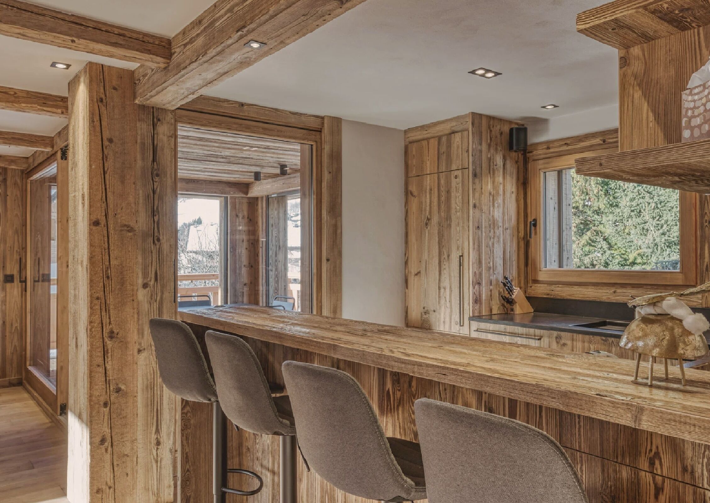 Un intérieur en bois avec un coin bar, des chaises et une fenêtre donnant sur un beau paysage.