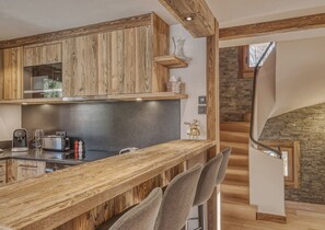 Eine Küche mit Holzschränken, einer Theke und einer Steintreppe.