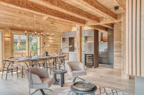 A wooden interior with a dining area, two chairs, a table, and a fireplace.