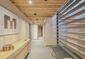 A hallway with wooden ceiling, a bench, a long wooden bench, and a wall-mounted shelf. - Modern Chalet with Panoramic Views (Les Avanchers-Valmorel)