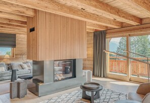 A modern interior with a fireplace, wooden ceiling, and a view of the outdoors.