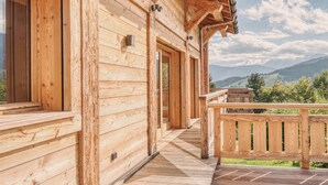 A wooden cabin with a wooden deck and a view of mountains. - Modern Chalet with Panoramic Views (Les Avanchers-Valmorel)