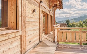 A wooden cabin with a wooden deck and a view of mountains. - Modern Chalet with Panoramic Views (Les Avanchers-Valmorel)