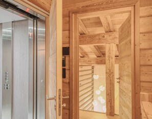A wooden interior with an elevator, a door, and a staircase. - Modern Chalet with Panoramic Views (Les Avanchers-Valmorel)