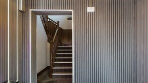 Een trap die leidt naar een tweede verdieping, met een houten leuning en een bordje met de tekst 'slaapkamers'.
