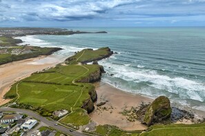 A coastal landscape with a beach, grassy areas, and a road leading to a building complex. - Finest Retreats | Sea 2 (Porth)