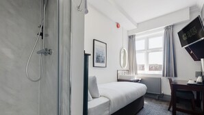 A hotel room with a bed, a desk, a shower, a window with curtains, and a wall-mounted TV. - Single Room in Watford ideal for Solo Travellers (Watford)
