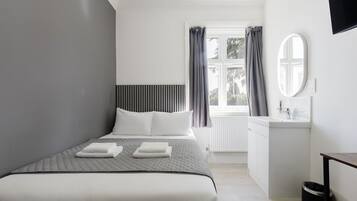 Un dormitorio moderno con cama, mesita de noche y ventana con cortinas.