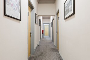 A hallway with framed pictures on the walls, a fire extinguisher, and a door labeled 'EXIT' at the end. - Spacious Twin Room Private Bathroom Great Location (Watford)