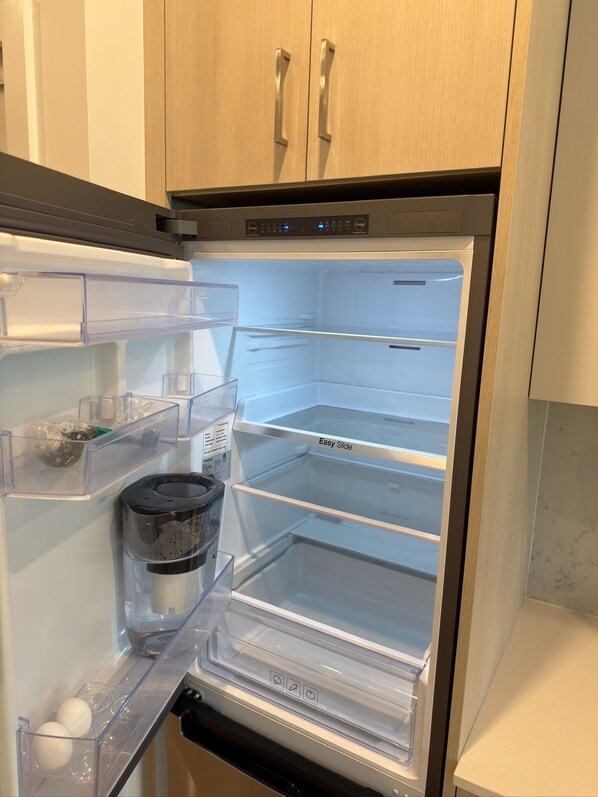 A stainless steel refrigerator with a freezer compartment, a water dispenser, and a transparent door.
