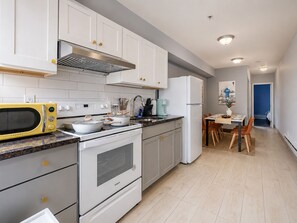 Una cocina moderna con armarios blancos, microondas, estufa y refrigerador.