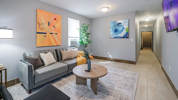 A modern living room with a grey sofa, a round coffee table, and artwork on the walls. - Lancaster Art Suite 2 - 4BR near Drexel & Penn (Philadelphia)