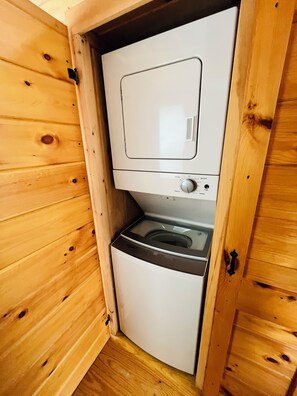 A compact, wooden-framed laundry room with a washing machine and dryer. - Cozy 1-bedroom cabin in terrific Newport with AC (Newport)