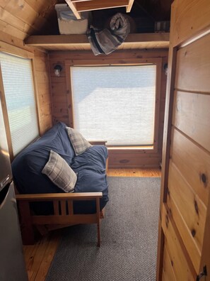 Ein kleines Zimmer mit Bett, Fenster und Tisch.