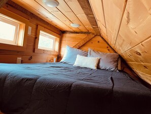 A bedroom with a bed, pillows, a window, and wooden walls. - Cozy 1-bedroom cabin in terrific Newport with AC (Newport)
