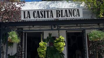 Un escaparate con un letrero que dice 'LA CASITA BLANCA' y elementos decorativos como una vaca y plátanos.