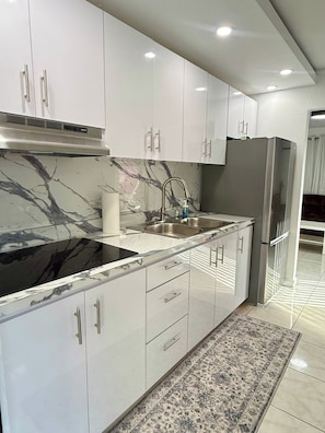 A modern kitchen with white cabinets, a black marble countertop, and a stainless steel refrigerator. - Central House w/Free Parking, Near Beach & (Carolina)