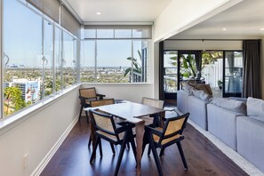 A modern living room with a dining area, large windows, and a view of the cityscape. - Miller Heights - Sunset Strip, unobstructed city and jetliner views (Los Angeles)