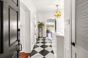A hallway with a black and white checkered floor, a door on the left, and a window on the right. - Miller Heights - Sunset Strip, unobstructed city and jetliner views (Los Angeles)