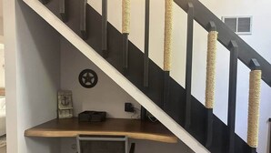 Un escalier avec un bureau et une chaise, une horloge et une prise de courant.