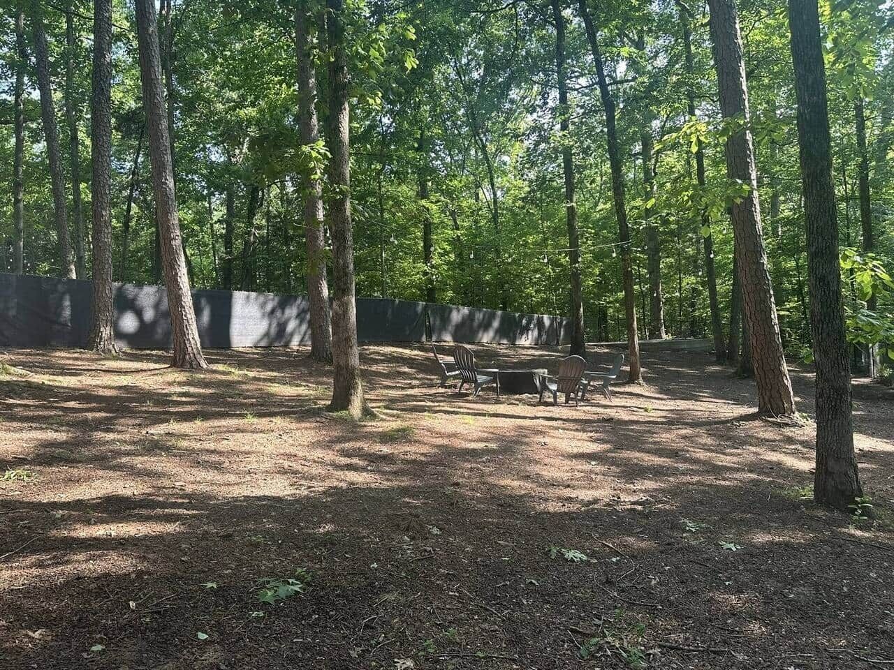 Zona boscosa con una mesa y sillas de picnic.