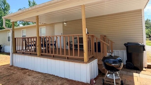 Un espacio al aire libre techado con cubierta de madera, una parrilla y un contenedor de basura.