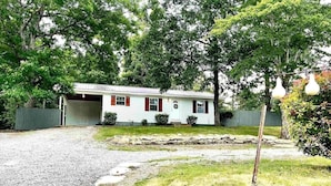 A single-story house with a garage, surrounded by trees and a gravel driveway. - Reel'em Inn fishing cabin in the Heart of Pickwick (Hardin County)