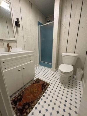 Une salle de bain avec un lavabo blanc, des toilettes et une douche.