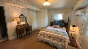 A bedroom with a bed, dresser, lamp, and a window. - The Bungalow at Bear Creek (Tishomingo County)