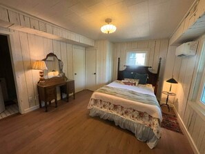 Une chambre à coucher avec un lit, une commode, une lampe et une fenêtre.