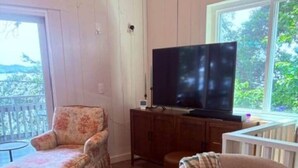A living room with a television, a chair, a sofa, and a window. - The Bungalow at Bear Creek (Tishomingo County)