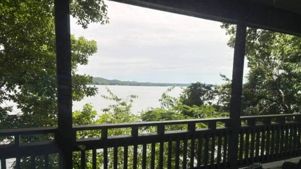 A covered outdoor area with a view of a body of water and trees. - The Bungalow at Bear Creek (Tishomingo County)